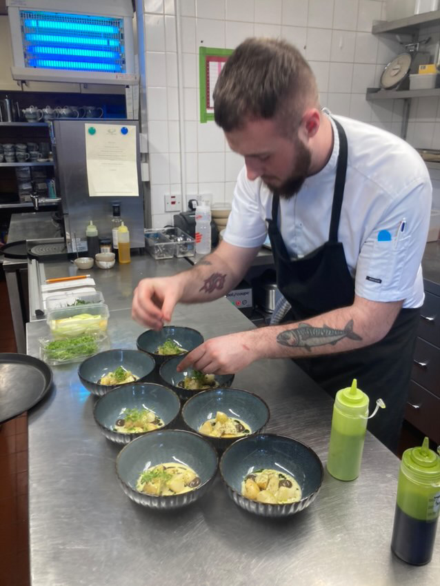 James Goodhew plating a dish in a professional kitchen